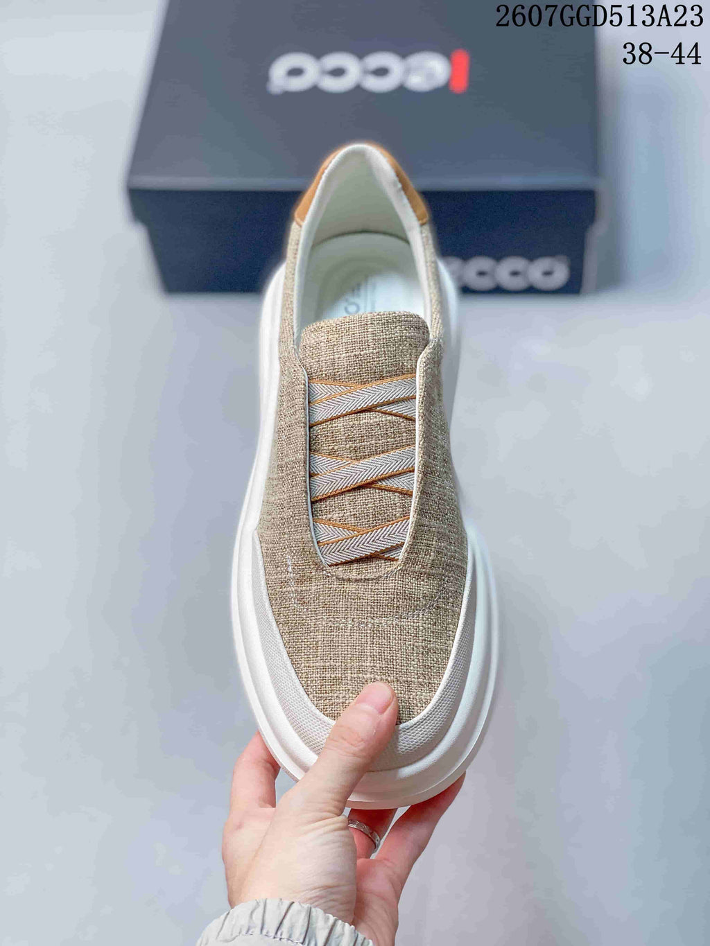 Top view of a beige ECCO slip-on sneaker showing the decorative cross-over lacing detail and white toe trim.