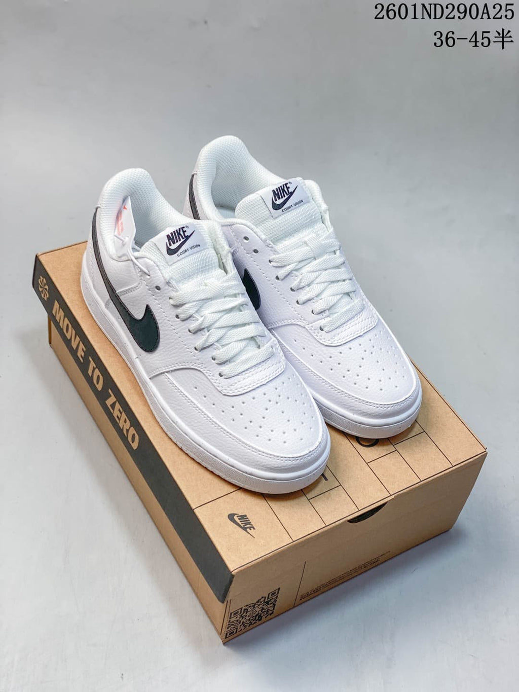 Pair of white Nike Court Vision low-top sneakers with dark navy Swoosh details displayed on a shoebox.