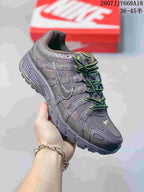 Angled side view of a dark gray Nike P-6000 sneaker showing the layered upper, side swoosh, and rugged outsole.