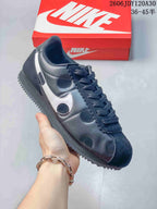 Angled side view of a dark Nike Classic Cortez sneaker with silver side detailing