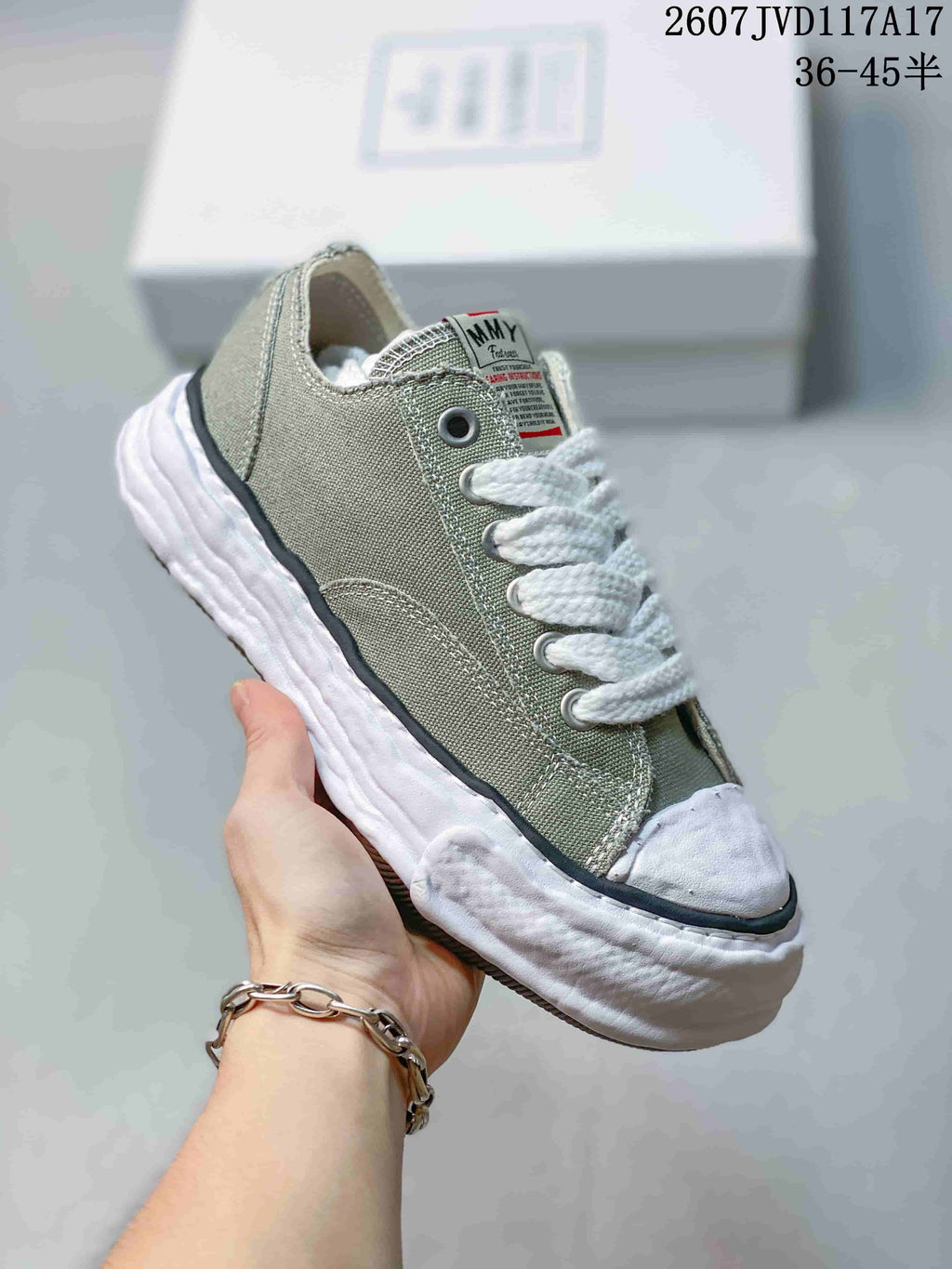 Close side view of an olive MMY canvas sneaker with contrast stitching, metal eyelets and a textured white sole.