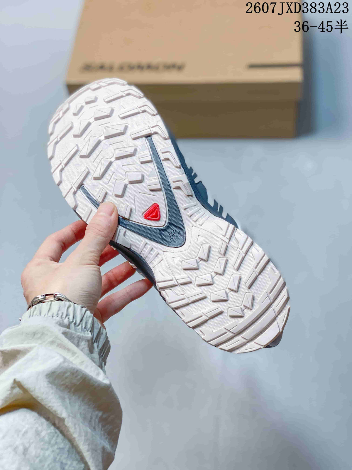 Underside view of the sneaker showing the light-colored lugged outsole and red heel detail.