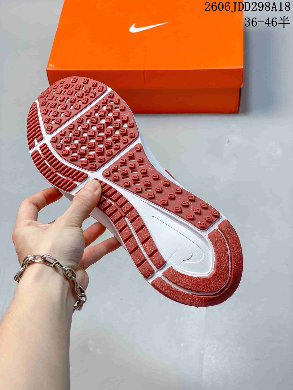 Close view of the sneaker outsole showing red traction sections and a patterned rubber tread.