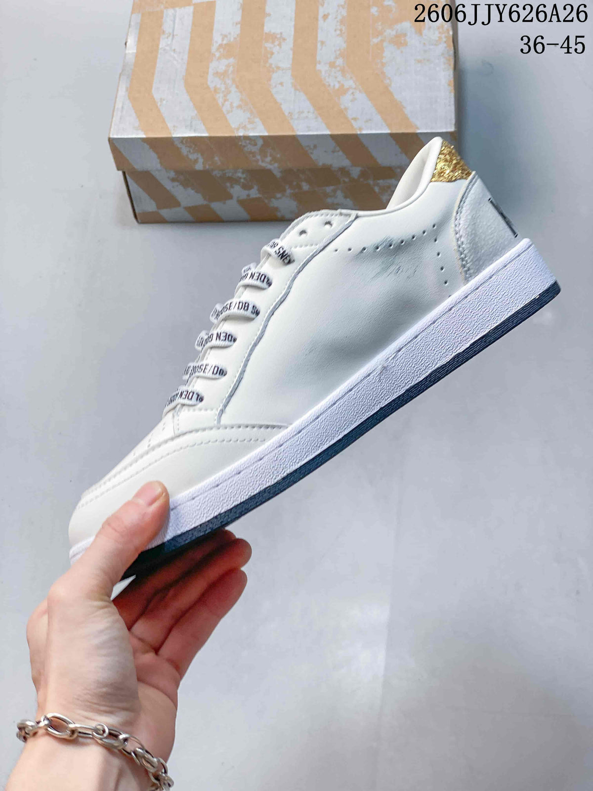 Side view of the white low-top sneaker showing perforations, a layered sole and gold heel accent.