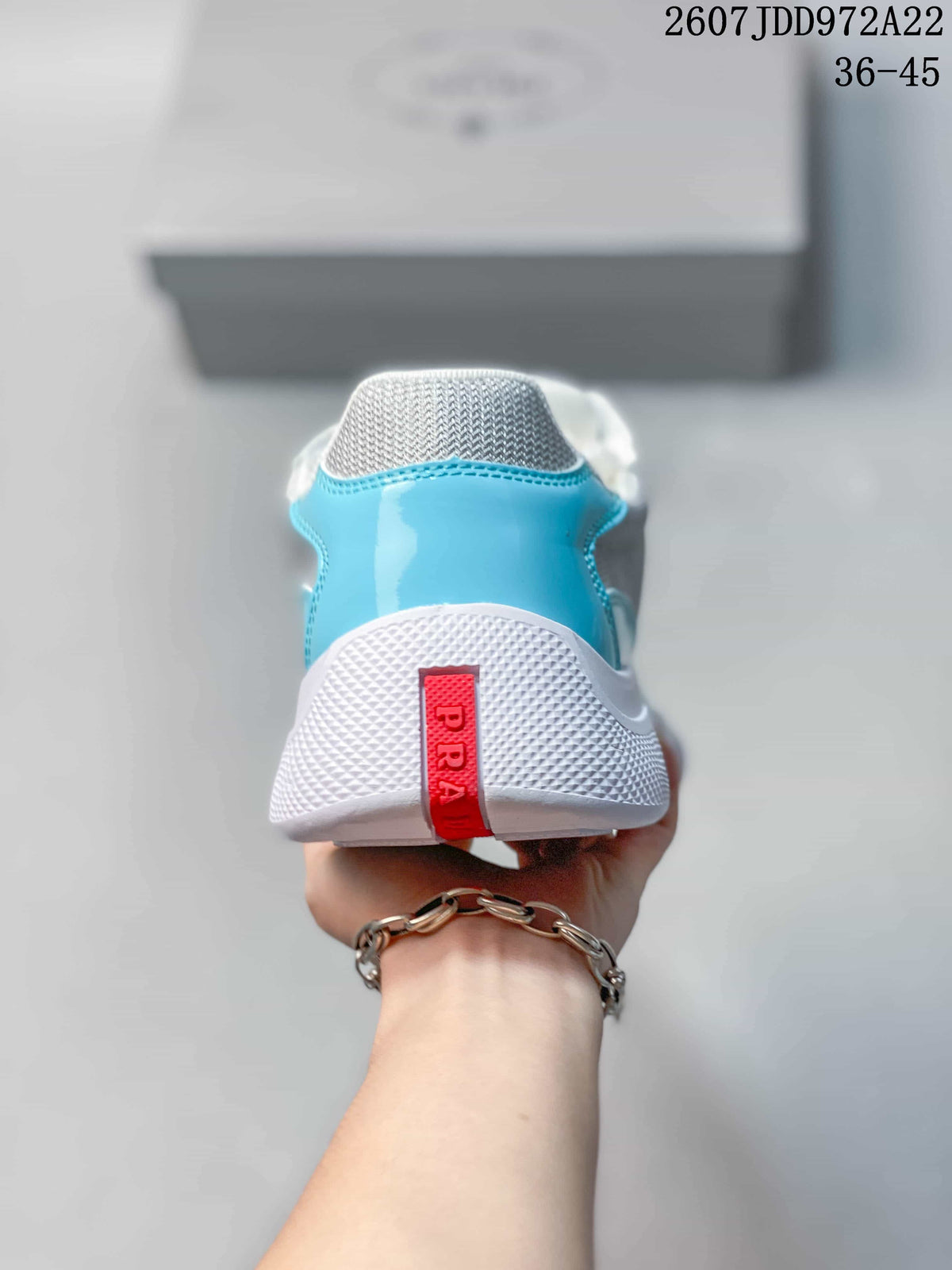 Rear view of the turquoise and white sneaker showing the white heel section and red branded pull detail.