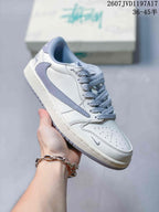 Close three-quarter view of a white sneaker with a grey side Swoosh, patterned laces and perforated toe box.