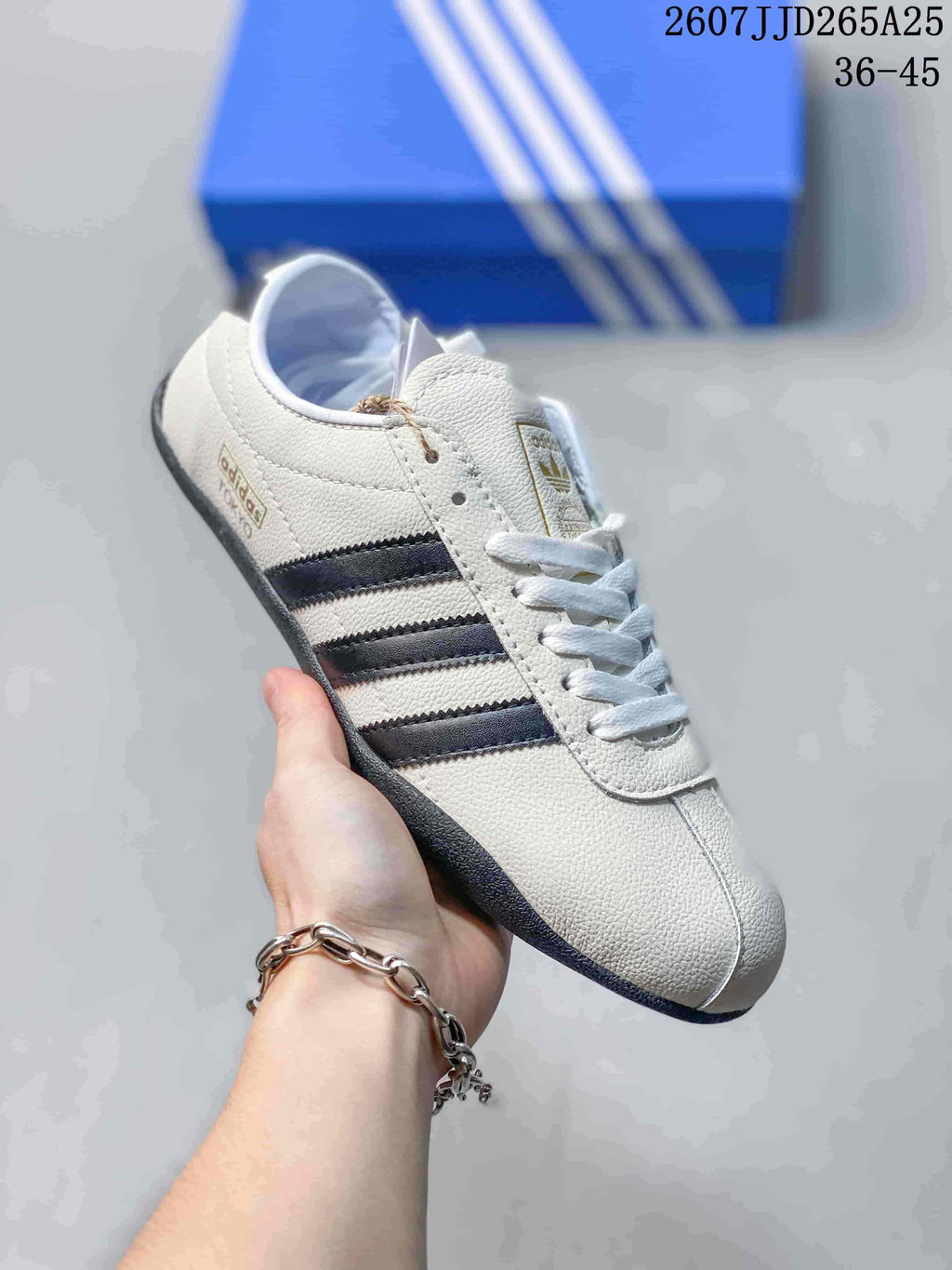 Angled side view of the white adidas sneaker showing black side stripes, gold-toned side branding, and a dark outsole.