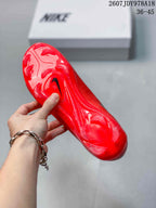 Underside view of a red soccer cleat showing the translucent red studded outsole and black Nike swoosh.