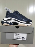 Balenciaga Triple S sneaker in dark blue-grey, white, black, and beige tones displayed on its box; the box label shows size C39 and style details.