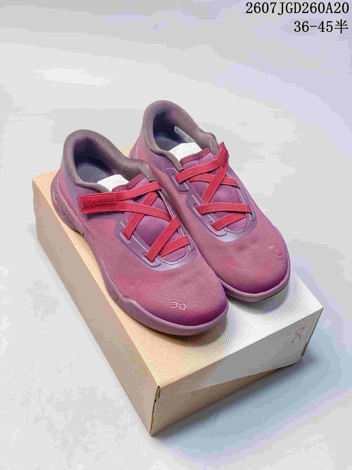 Pair of pink On Cloudnova Moon sneakers displayed on a shoebox with contrasting red-pink straps and padded collars.
