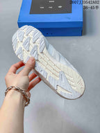 View of the patterned outsole on the white sneakers, with the collaboration-branded box in the background.