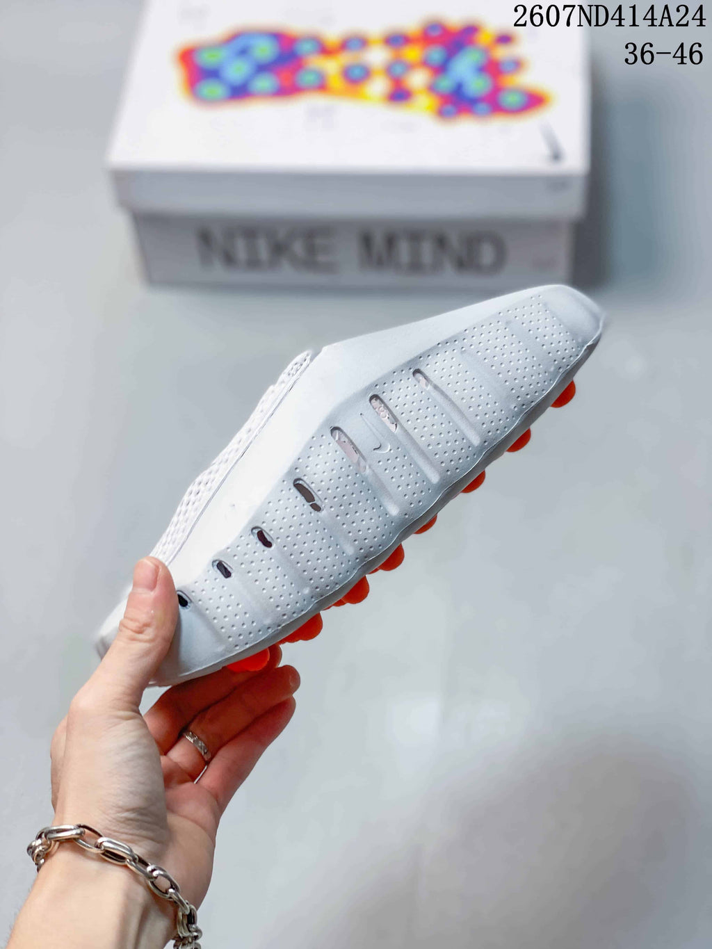 Side and outsole view showing perforated panels, a Swoosh detail, and orange outsole elements.