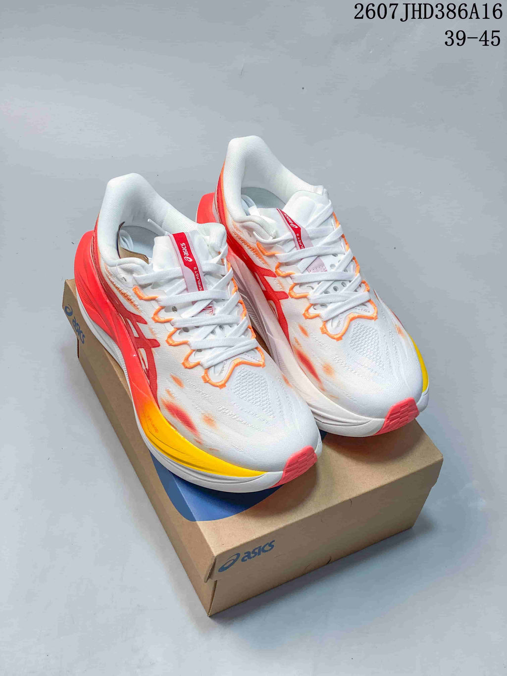 Pair of white ASICS running shoes with red, orange and yellow accents displayed on an ASICS shoe box.