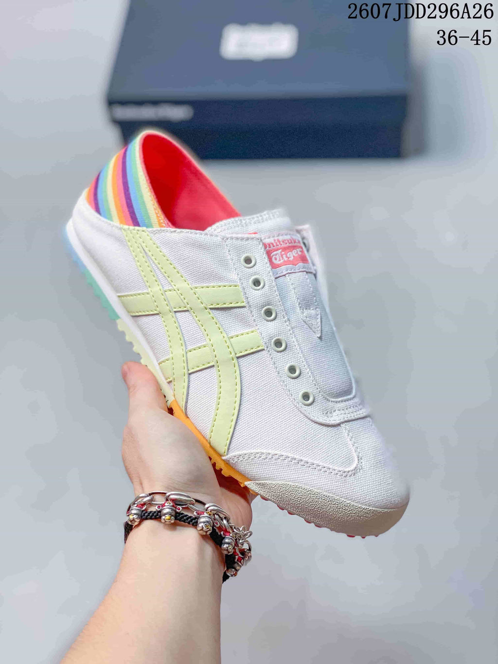 White Onitsuka Tiger Mexico 66 slip-on sneaker with pale yellow side stripes, a rainbow-striped heel, and a colorful outsole.