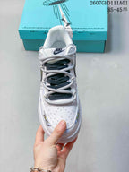 Front view of a white low-top sneaker with perforated toe and gray-and-dark lace arrangement