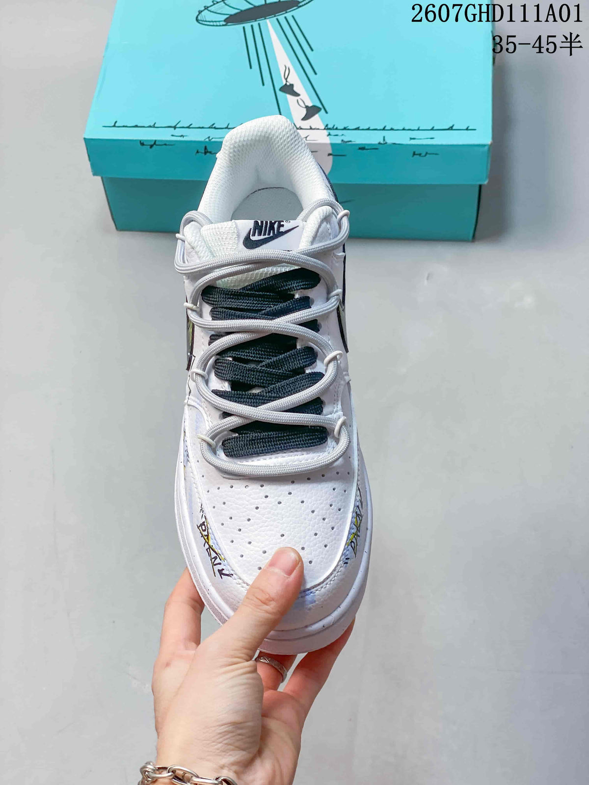 Front view of a white low-top sneaker with perforated toe and gray-and-dark lace arrangement