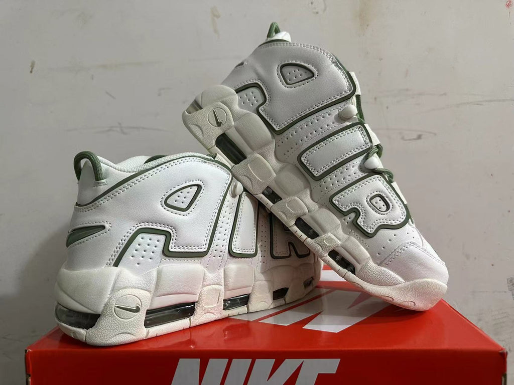Angled view of white Nike sneakers with oversized AIR lettering and green details