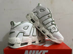 Angled view of white Nike sneakers with oversized AIR lettering and green details