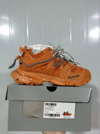 Side view of the orange Balenciaga Track 7000 sneaker resting on its box; the label identifies the Track sneaker, orange color, and sample size E 41.