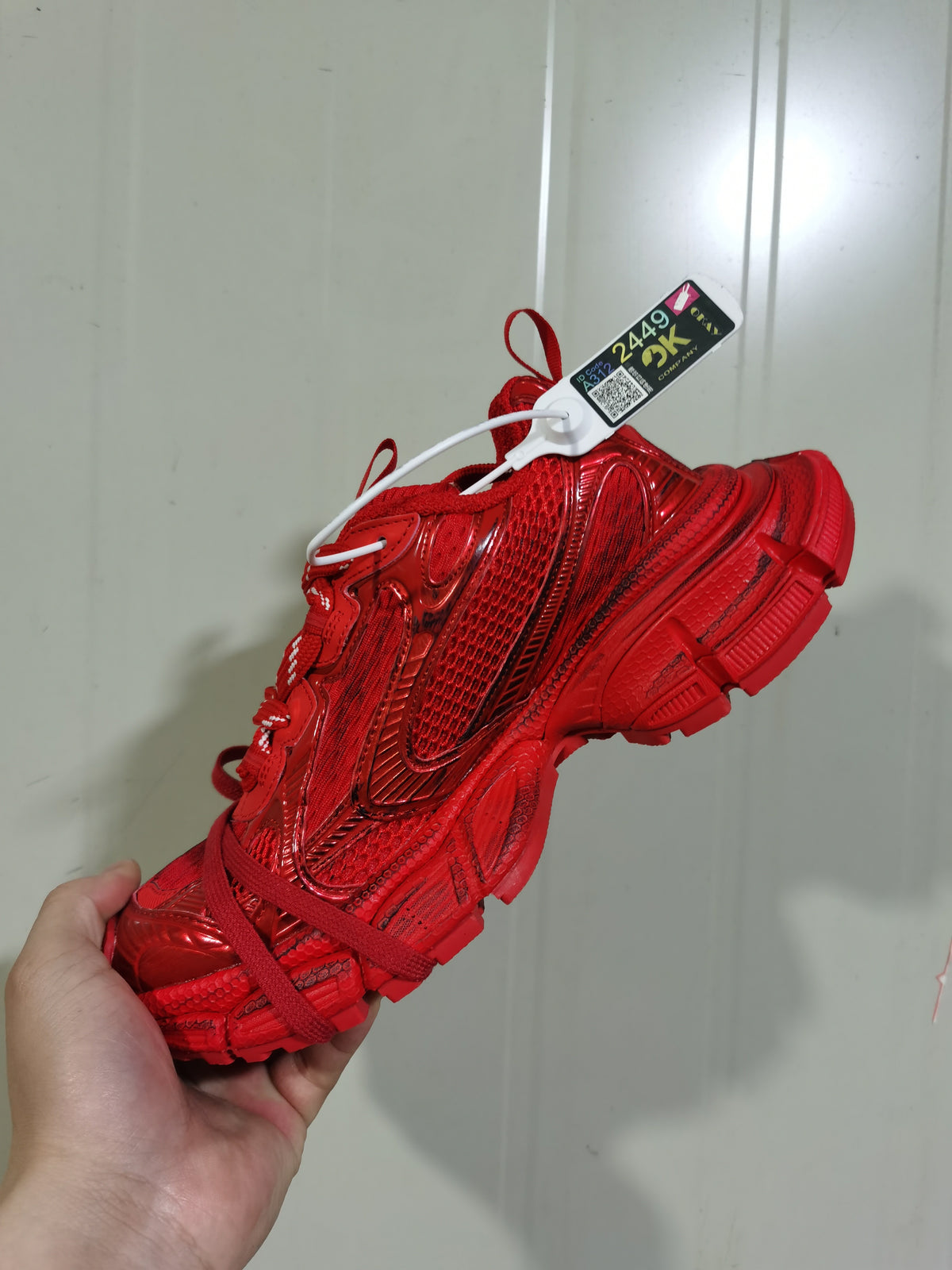 Close-up side view of a red monochrome sneaker showing the textured upper, layered panels, side Swoosh design, and red laces.
