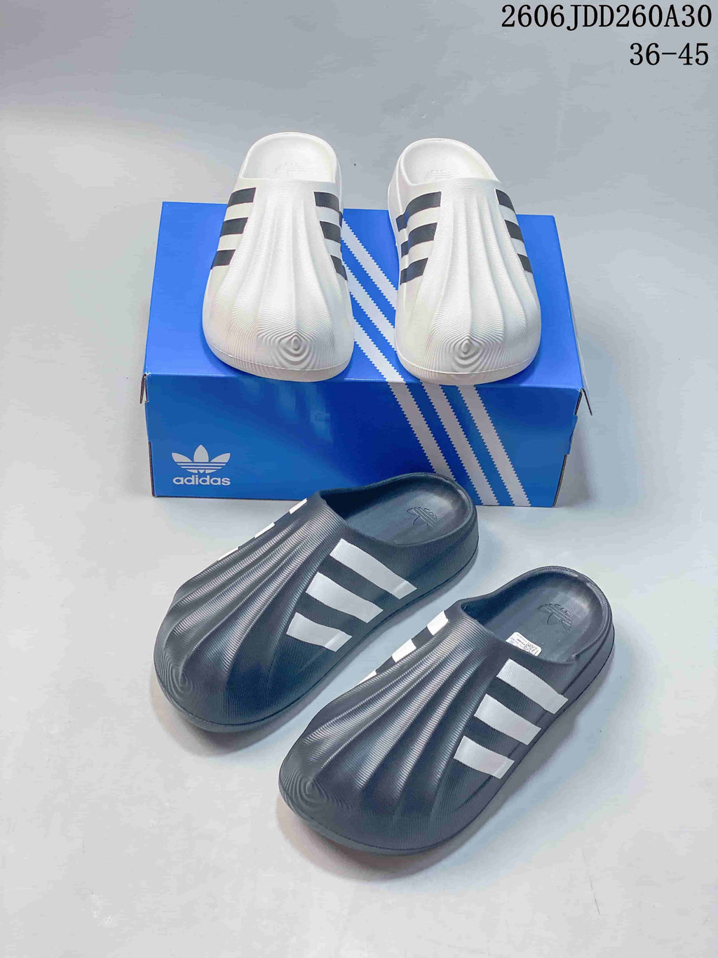 White and charcoal adiFOM Superstar mule pairs displayed together.