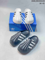 White and charcoal adiFOM Superstar mule pairs displayed together.