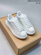 Pair of white textured platform sneakers with pale blue heel panels, shown on a box.