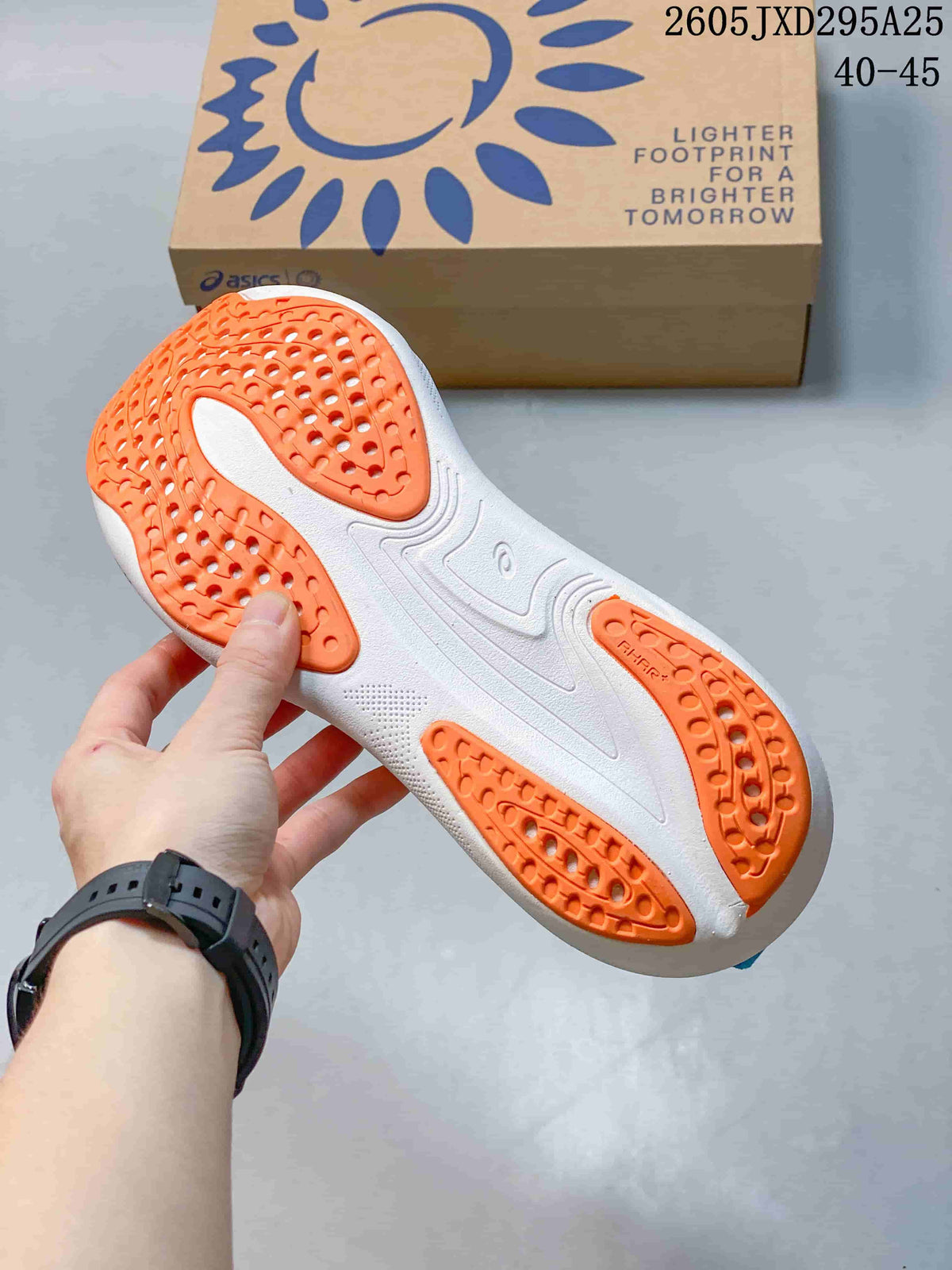 Outsole view of the ASICS running shoe showing orange tread sections and a white sole