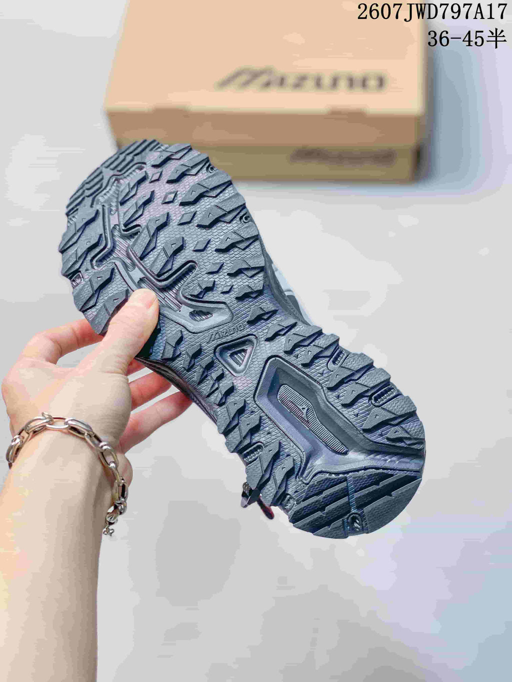 Close-up of the rugged lugged outsole on a silver and black Mizuno sneaker.