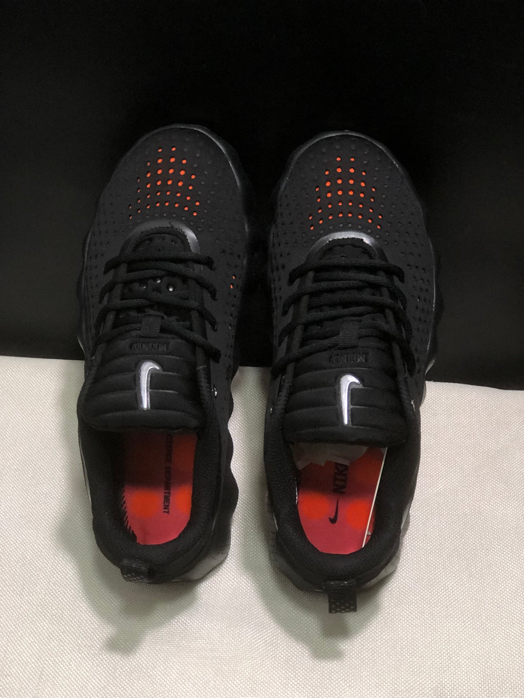 Top view of the pair showing perforated toe boxes, black laces, and orange insoles.