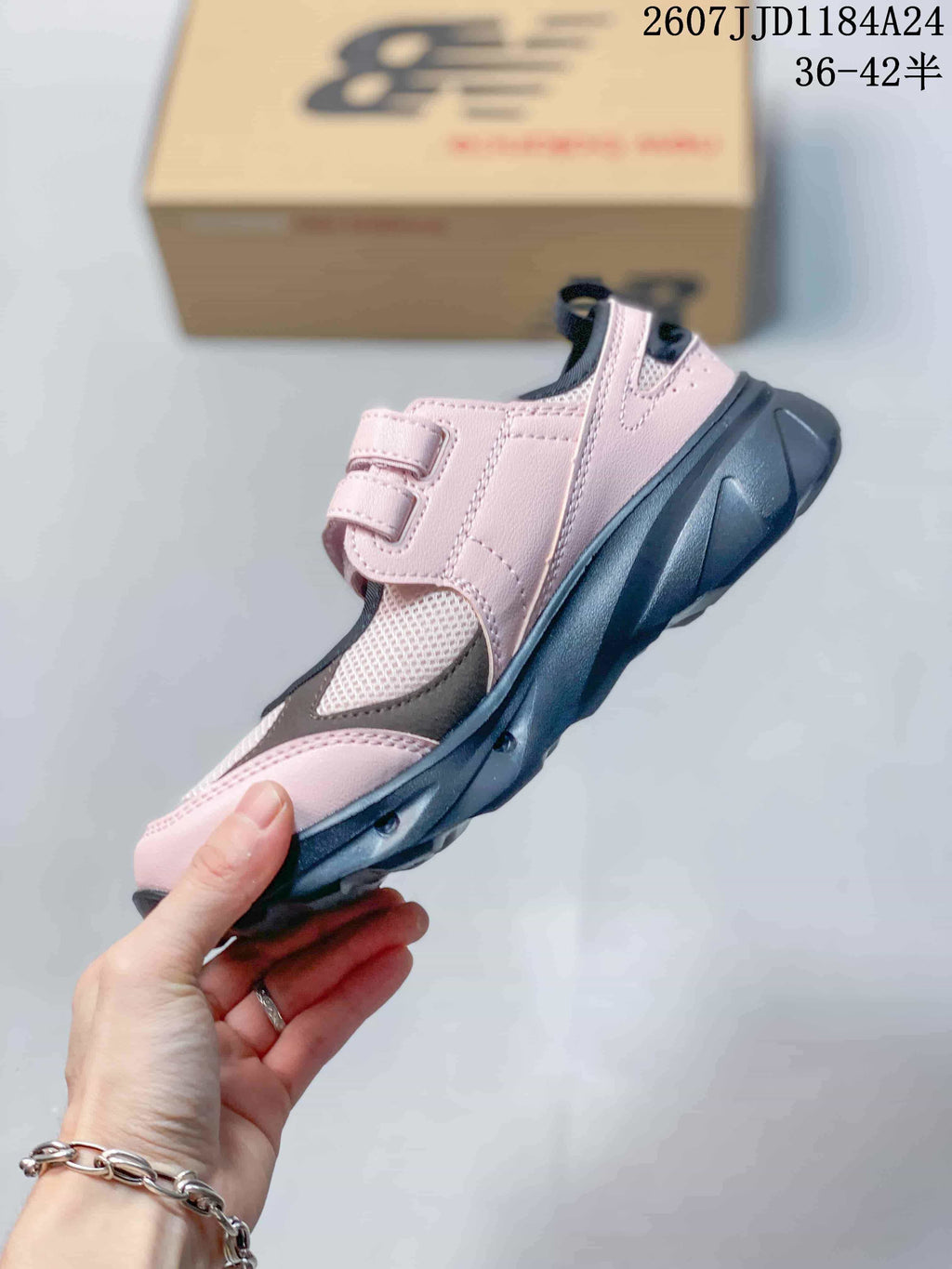 Side view highlighting the pink upper, adjustable strap, mesh panel, layered overlays, and chunky dark outsole.