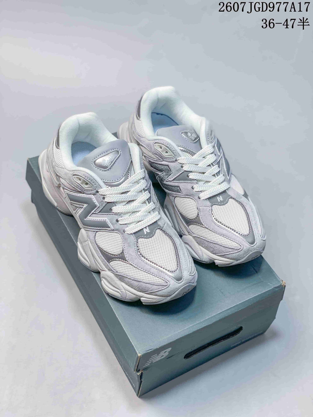Pair of gray New Balance 9060 sneakers displayed on a shoebox, with the style code and size range visible above.
