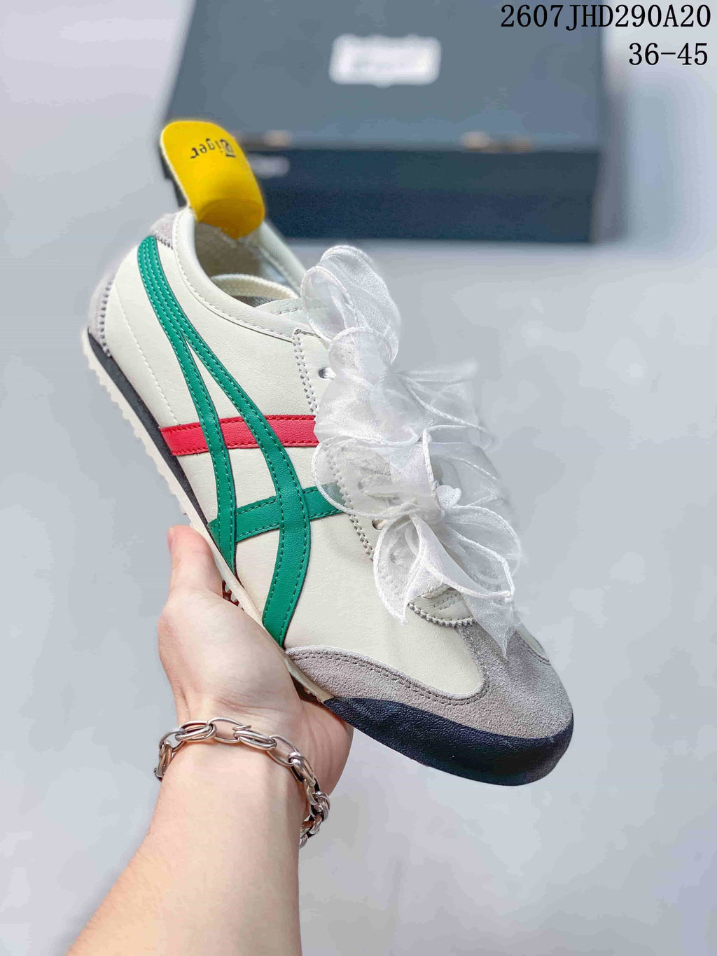 White sneaker with green and red side stripes, gray toe detailing, and translucent ribbon laces.