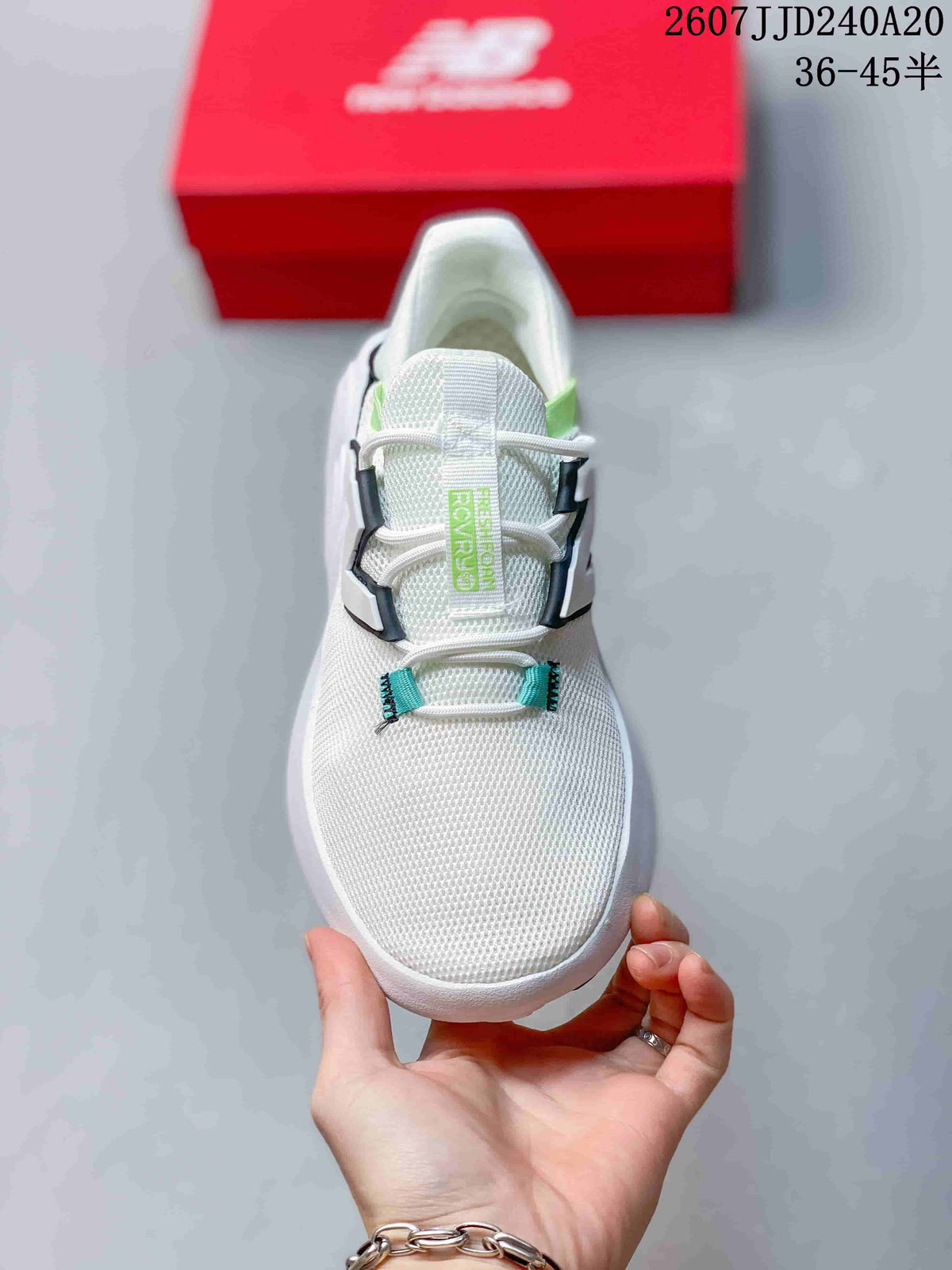 Top view of the white New Balance sneaker showing its perforated-looking upper, laces, light green tongue branding and black-edged side structure.