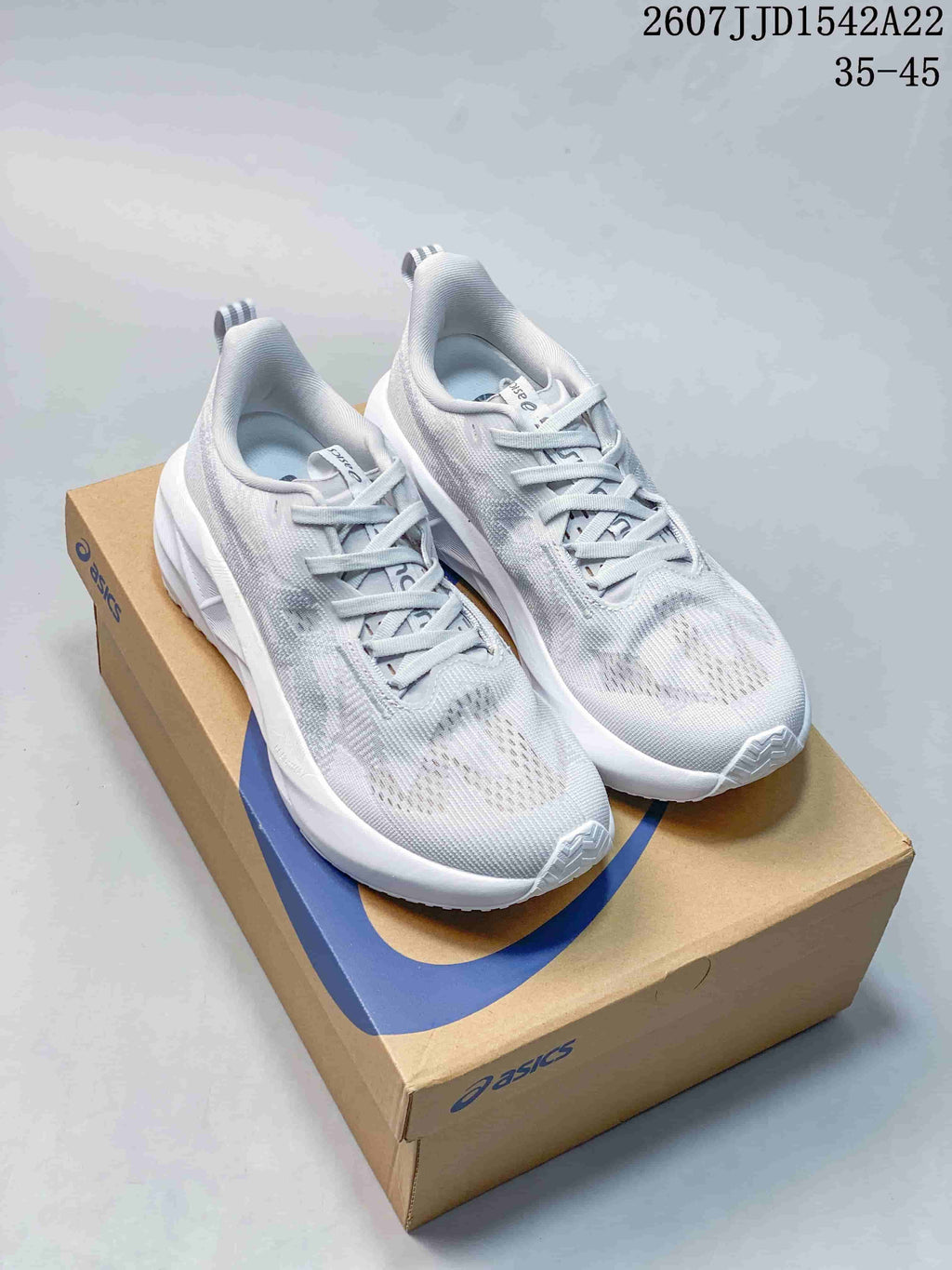 Pair of light white and gray ASICS GEL-NOVABLAST 5 LE running shoes displayed on an ASICS shoebox; image text shows JJD1542A22 and 35–45.