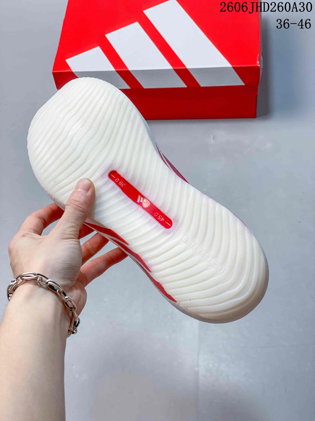 Underside of the adidas shoe showing a white ridged sole and red center detail