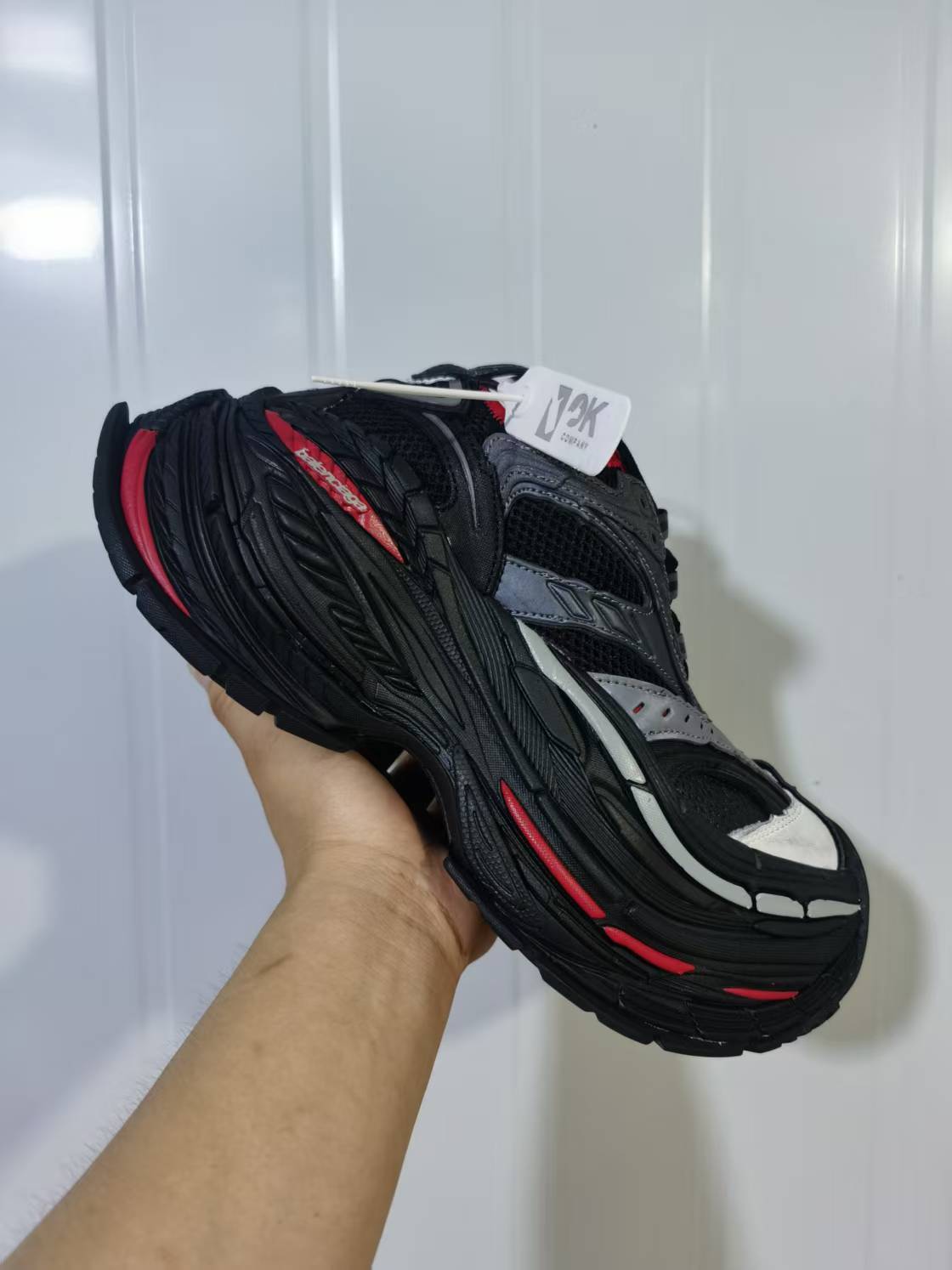 Top and side angled view highlighting the black mesh upper, red accents, light forefoot detail, and textured platform sole.