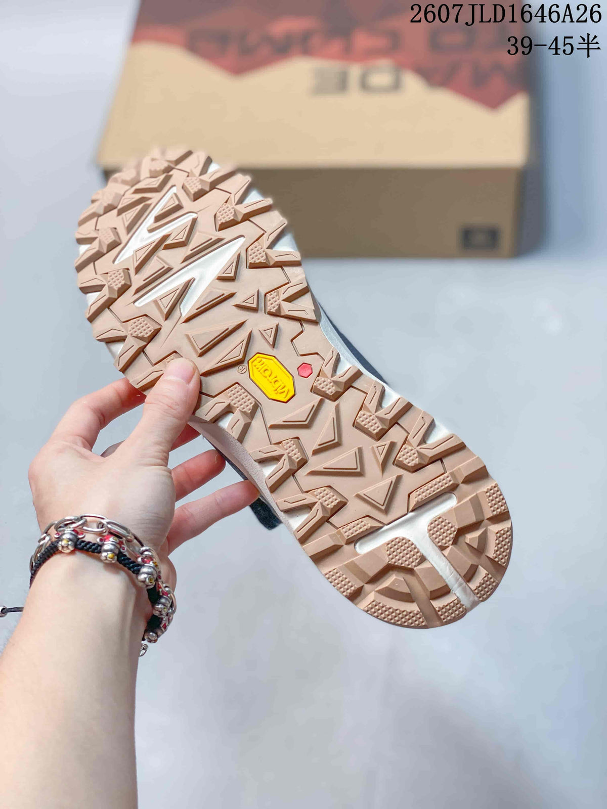 Close view of the tan lugged outsole with deep geometric tread and a yellow outsole insert.