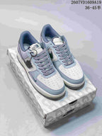 Pair of pale blue-gray and off-white Nike Air Force 1 Low sneakers displayed on a patterned shoebox.