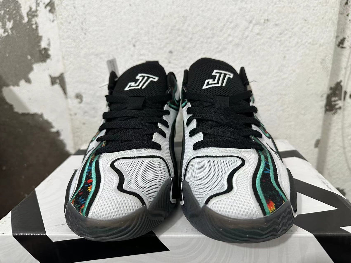 Front view of black, white, and green Jordan basketball shoes with floral-patterned side accents.
