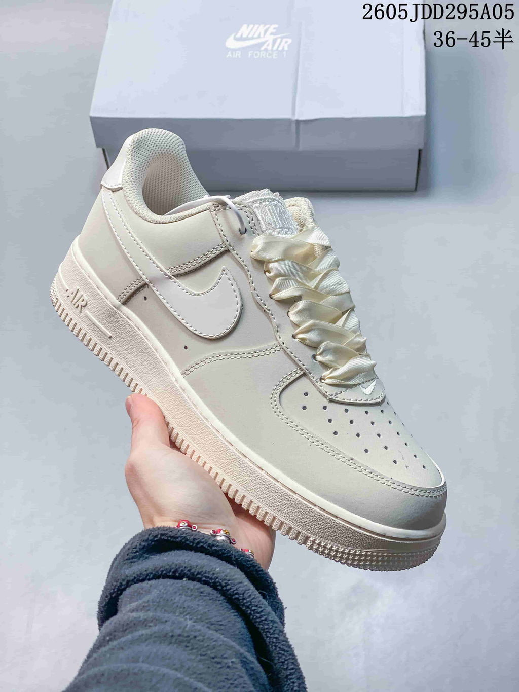Angled side view of a cream Nike Air Force 1-style sneaker showing the Swoosh, Air heel detail, and rubber outsole.