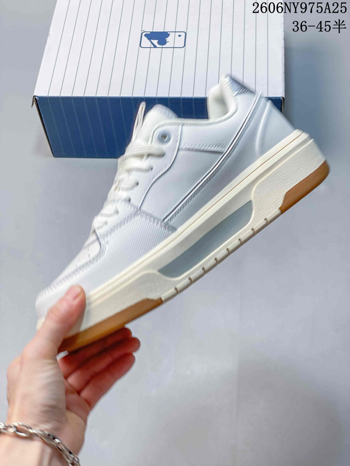 Side profile of the white and light-gray low-top sneaker showing the layered panels, raised sole, and gum outsole.