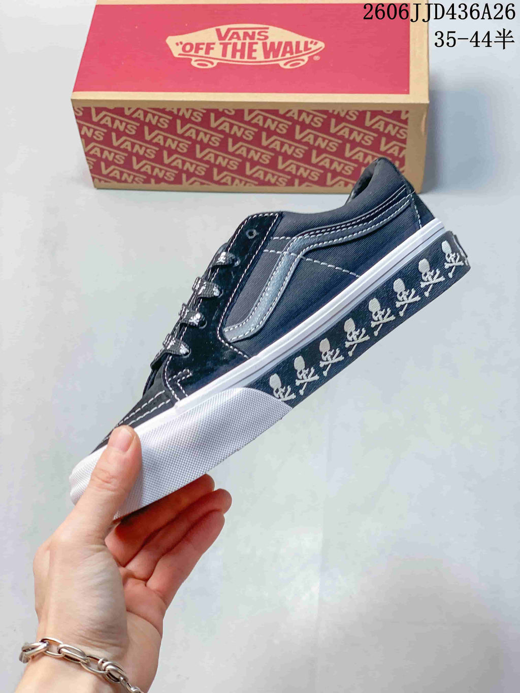Side profile showing the black low-top upper, contrast stitching, side stripe, skull-print sidewall, and white rubber sole.