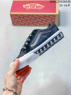Side profile showing the black low-top upper, contrast stitching, side stripe, skull-print sidewall, and white rubber sole.