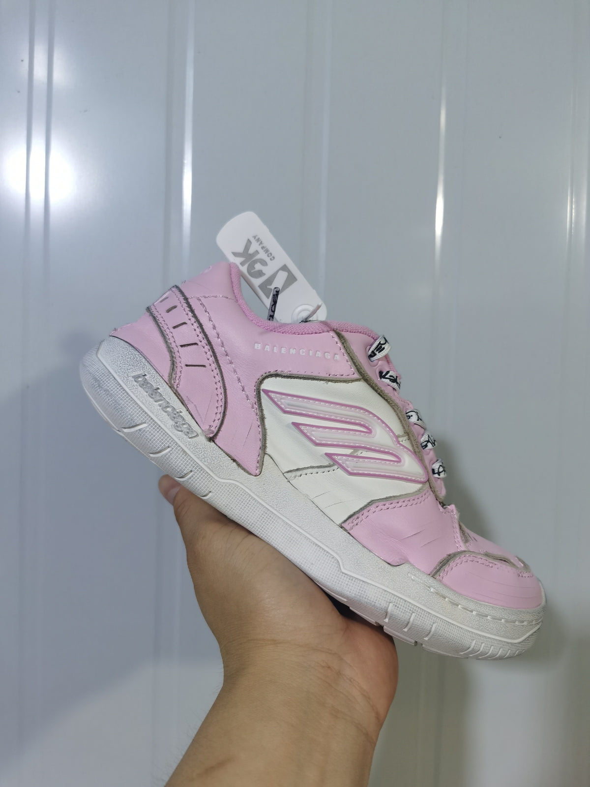 Angled close-up of the pink and white Balenciaga Hamptons sneaker showing the layered upper, side logo detail, and branded laces.
