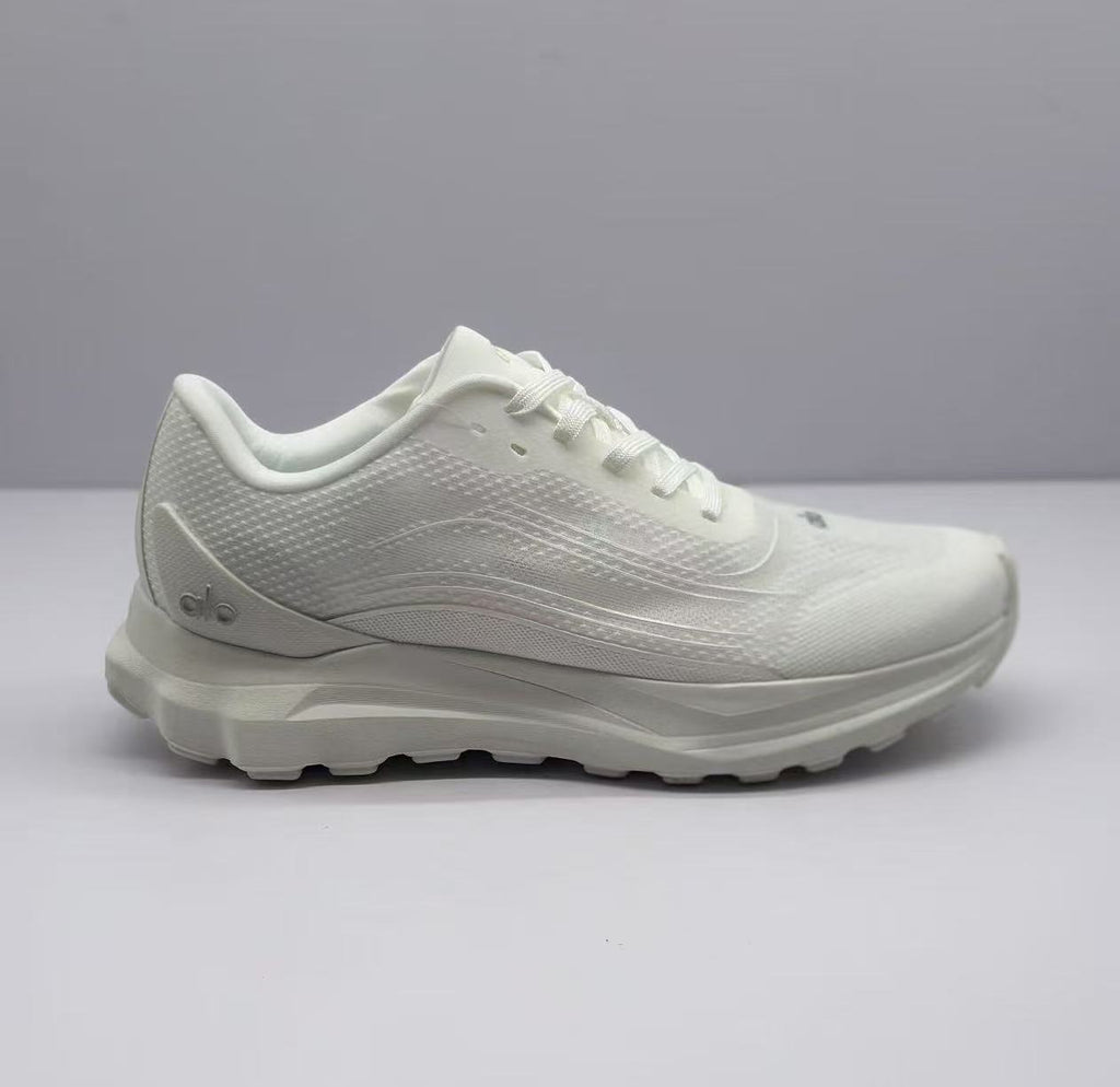Side view of an all-white Alo low-top sneaker with a textured upper and layered sole.