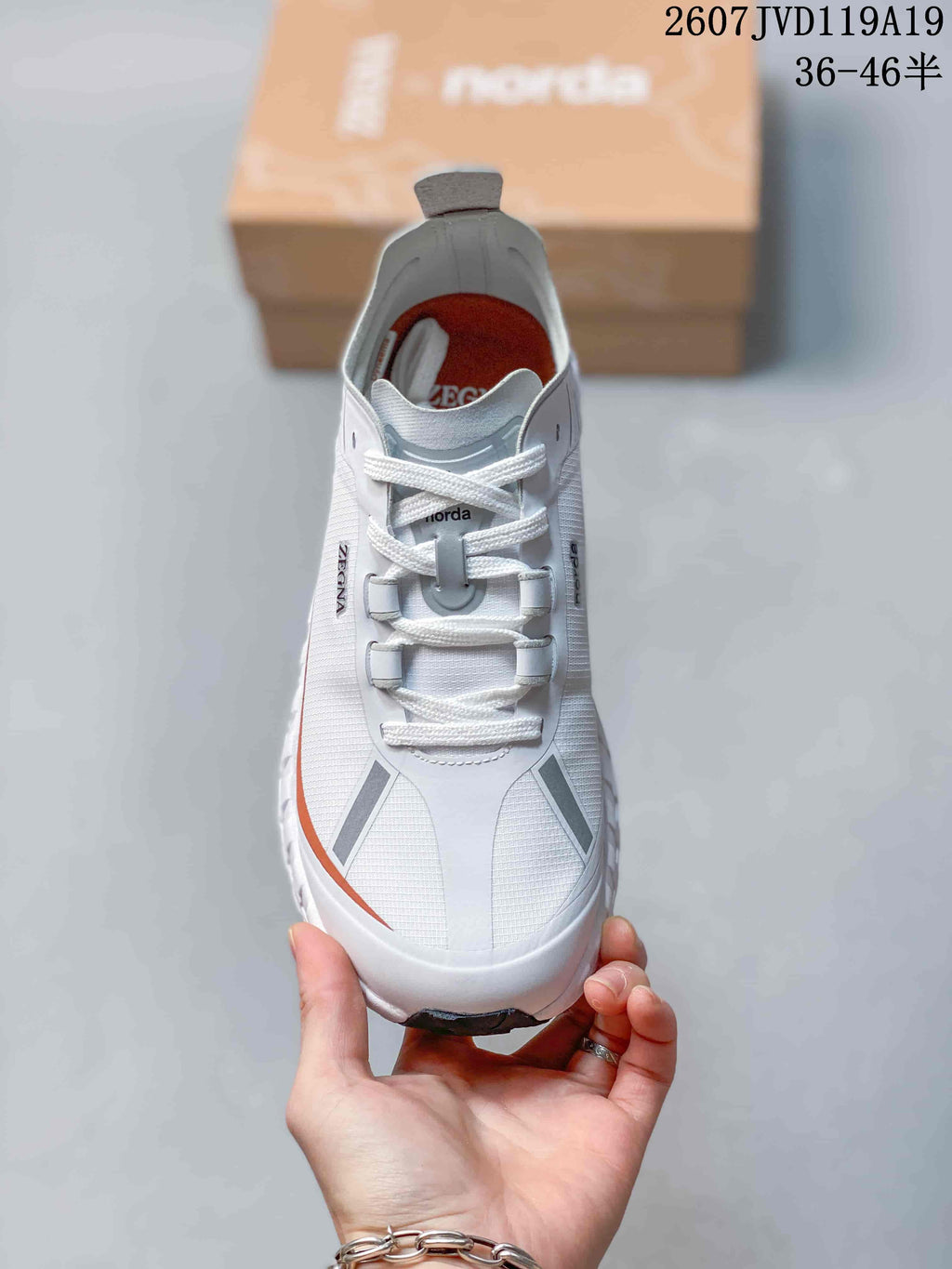 Top-down view of the white lace-up sneaker showing the gray tongue detail, orange interior lining, and reflective-looking gray overlays.