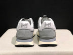 Rear view of the grey sneakers showing BAPE STA heel branding, padded collars, cream midsoles, and black outsoles.