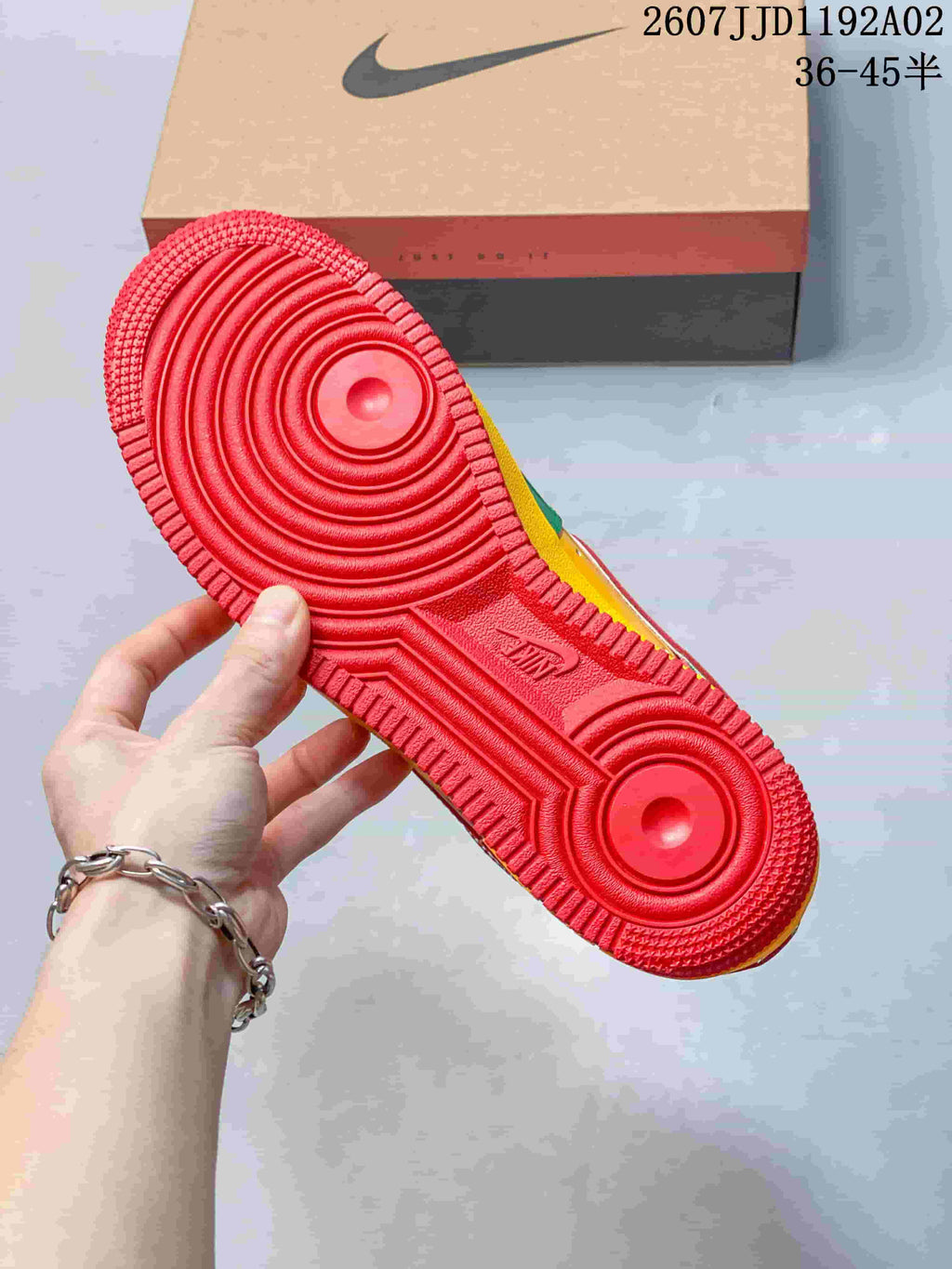 View of the red outsole on a green, yellow, and red low-top sneaker