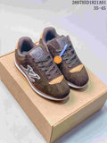 Pair of dark brown Buttersoft low-top sneakers with tonal laces, contrasting side emblems and light accents, displayed on a box.